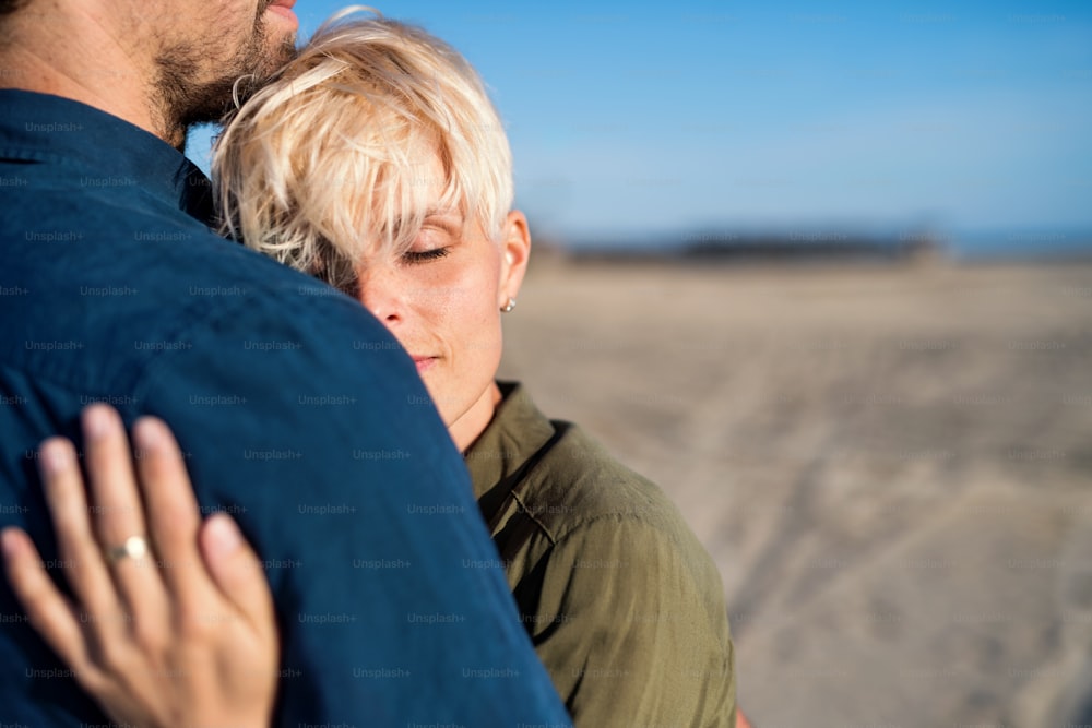 A midsection of young couple standing outdoors on beach, hugging. Copy space.