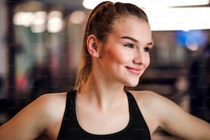 Ein Porträt eines schönen jungen Mädchens oder einer Frau, die in einem Fitnessstudio steht.