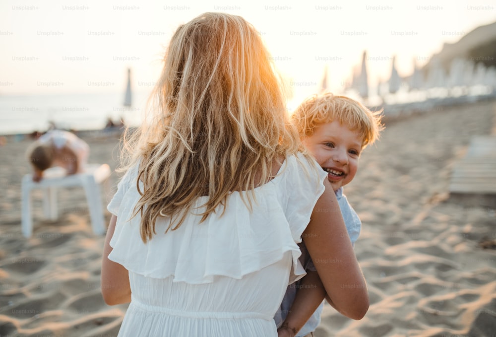 Una giovane madre con un bambino che si diverte sulla spiaggia durante le vacanze estive.