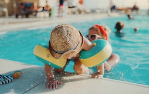Um menino pequeno e feliz com braçadeiras e sua mãe nadando na água nas férias de verão.