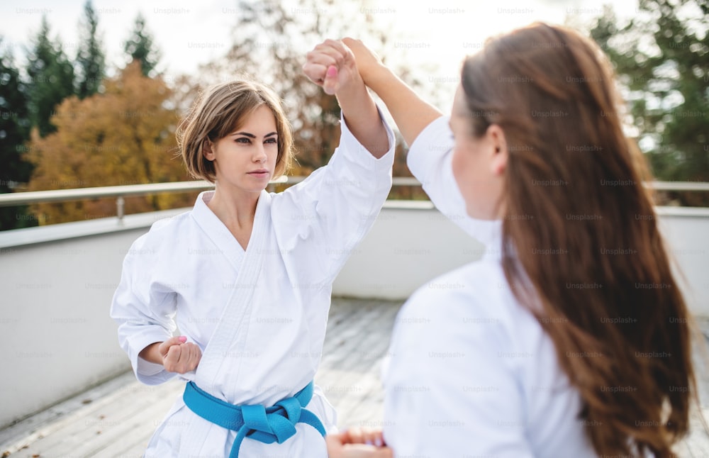 Two young women practising karate outdoors on terrace.