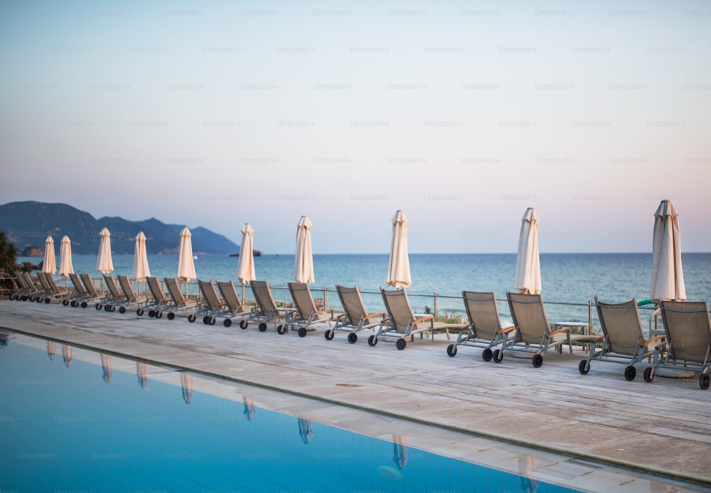 Liegestühle und Sonnenschirme in einer Reihe am tropischen Strand, Sommerurlaubskonzept.