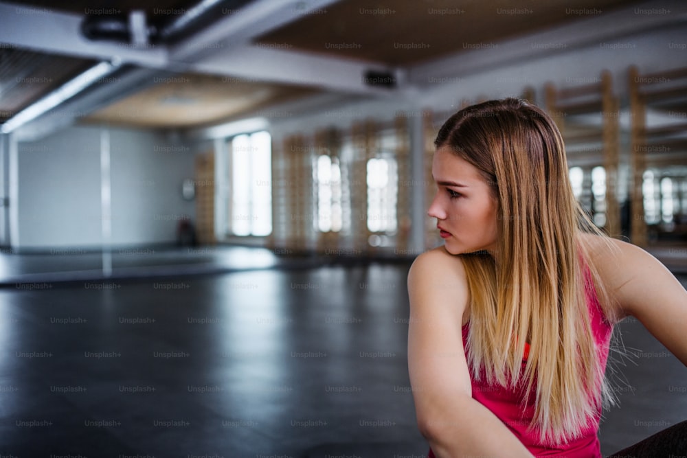 Un ritratto di giovane ragazza o donna triste e frustrata seduta in una palestra. Copia spazio.