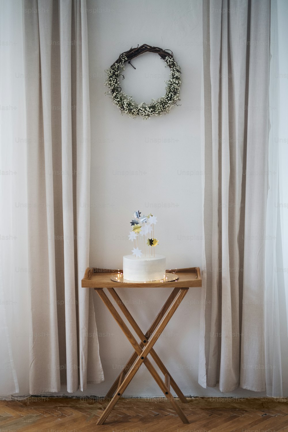 A white modern birthday cake on a table on an indoor party. Copy space.