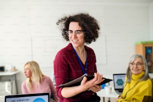 Retrato de un profesor con personas mayores que asisten a la clase de informática y tecnología, mirando a la cámara.