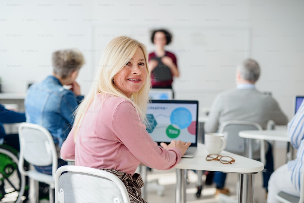 Porträt eines Seniors, der den Computer- und Technologieunterricht besucht und in die Kamera schaut.