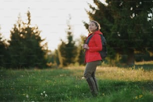 Side view of young woman on a walk outdoors on meadow in summer nature, walking.
