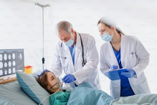 Doctors and infected patient in quarantine lying in bed in hospital, coronavirus concept.