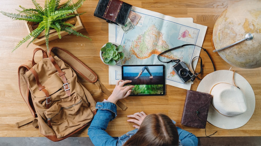 Top view of unrecognizable young woman with maps planning vacation trip holiday, desktop travel concept.