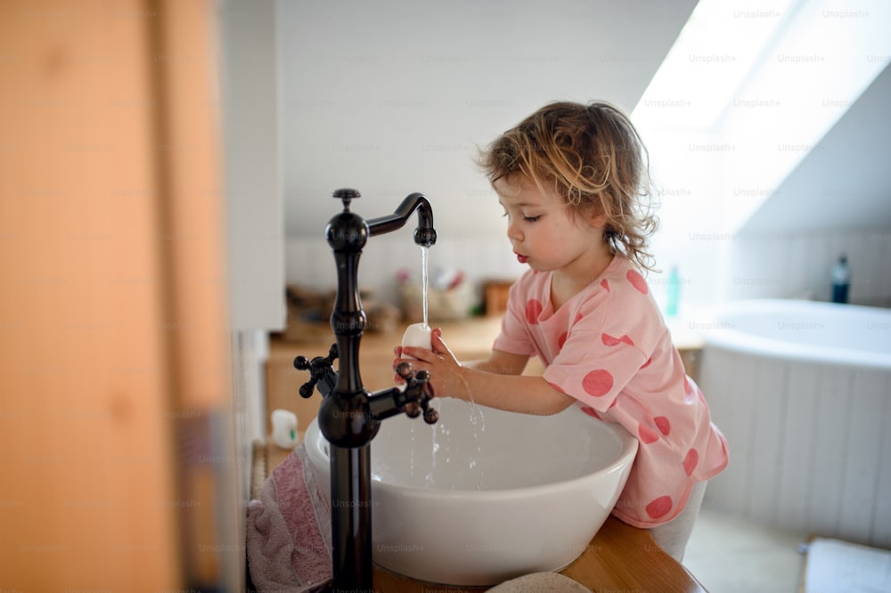 手を洗う集中した小さな幼児の女の子、コロナウイルス、検疫のコンセプトの側面図。