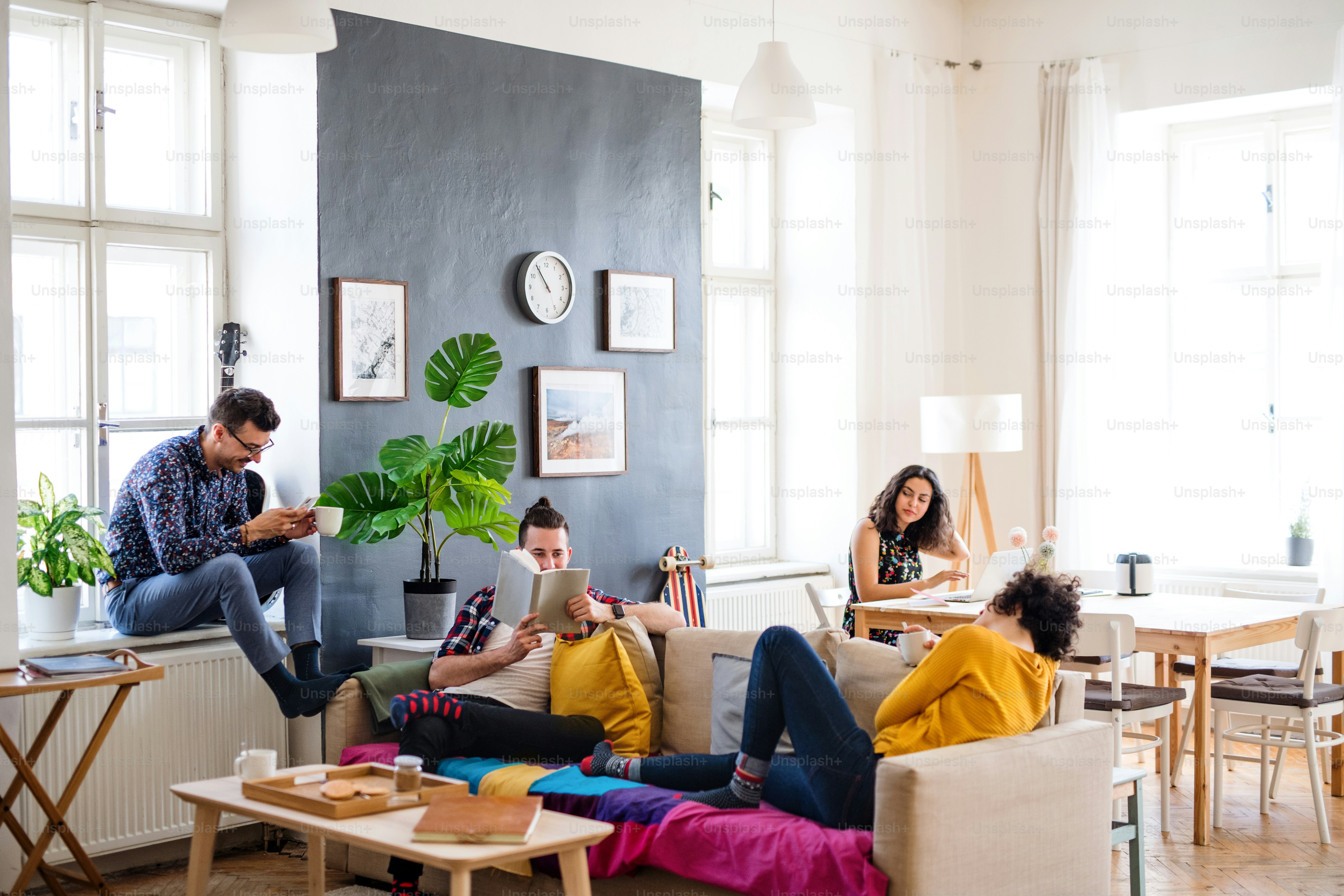 Un grupo de jóvenes amigos alegres que se relajan en el interior, concepto de casa compartida.
