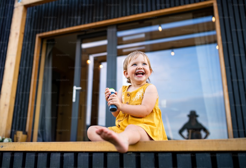 Happy small child playing outdoors, weekend away in container house in countryside.