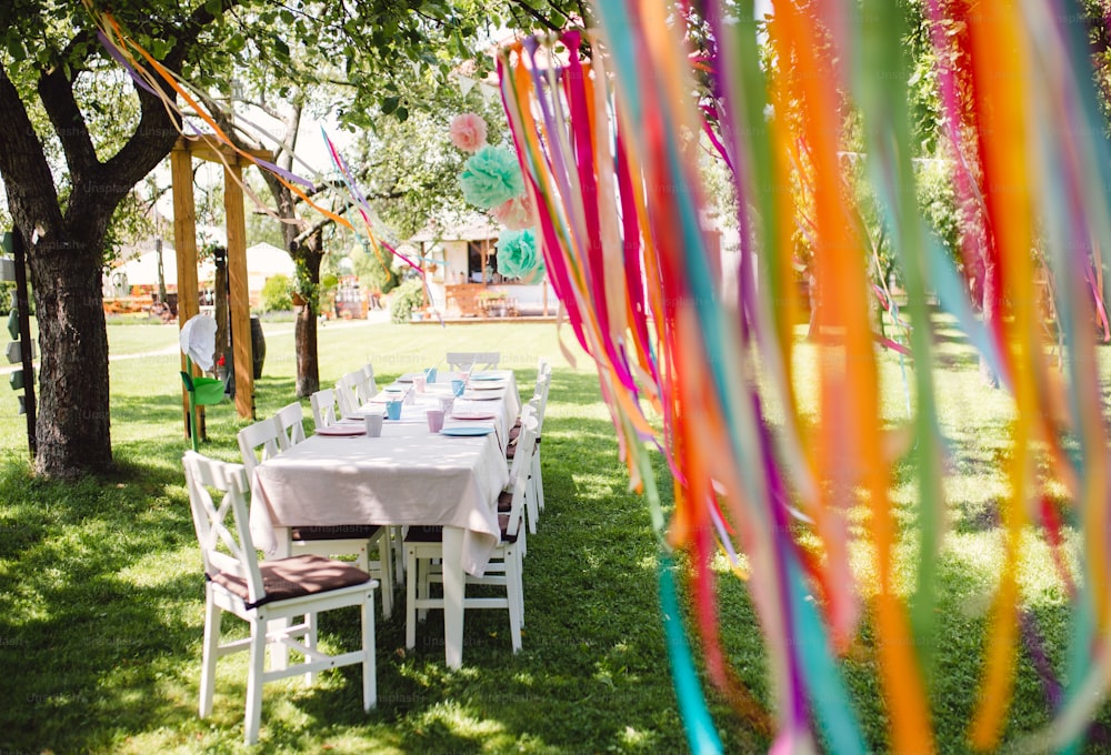 Uma mesa posta para a festa de aniversário das crianças ao ar livre no jardim no verão, conceito de celebração.