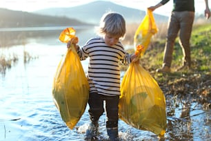 Padre irriconoscibile con figlio piccolo che raccoglie rifiuti all'aperto nella natura, concetto di plogging.