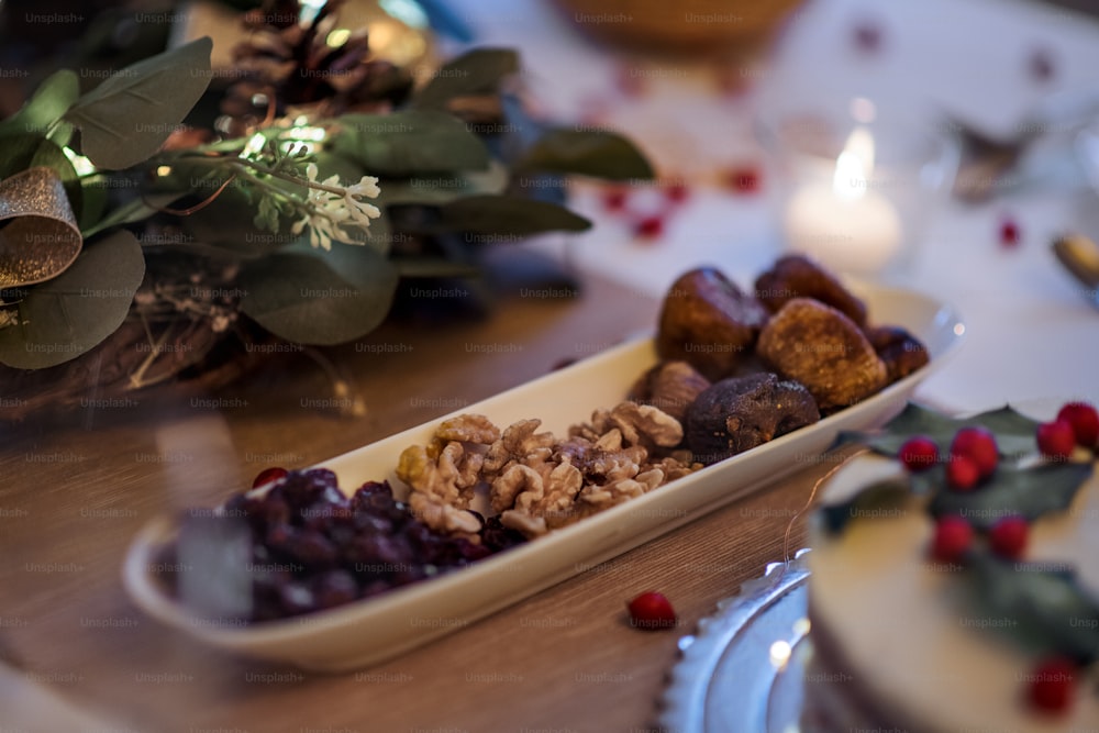 Un primo piano di frutta secca e noci sulla tavola apparecchiata per la cena a Natale, vista dall'alto.