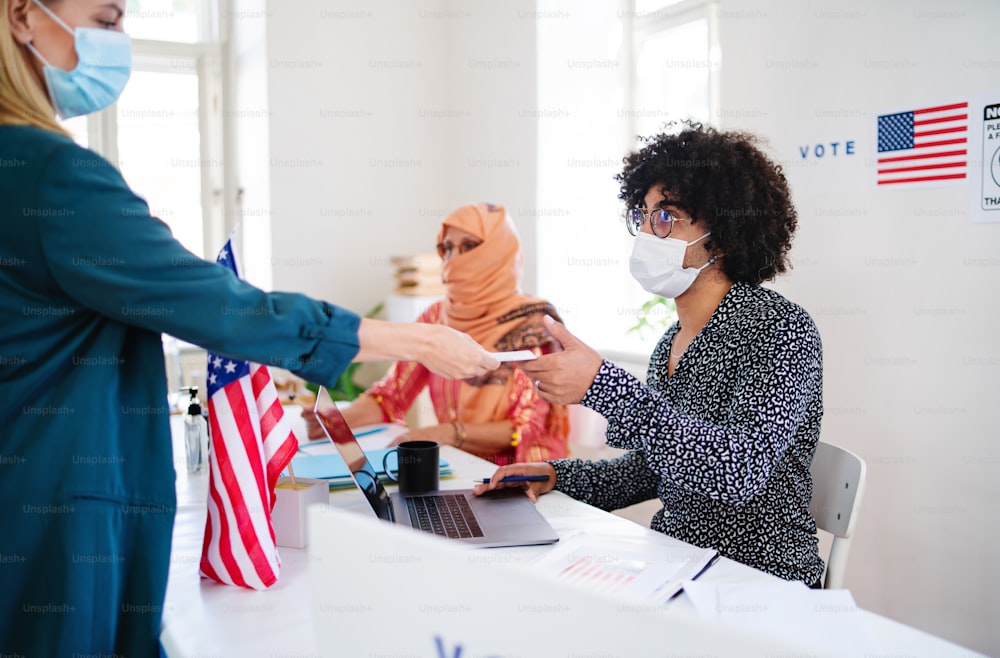 投票所で投票するフェイスマスクをした人々のグループ、米国の選挙とコロナウイルス。