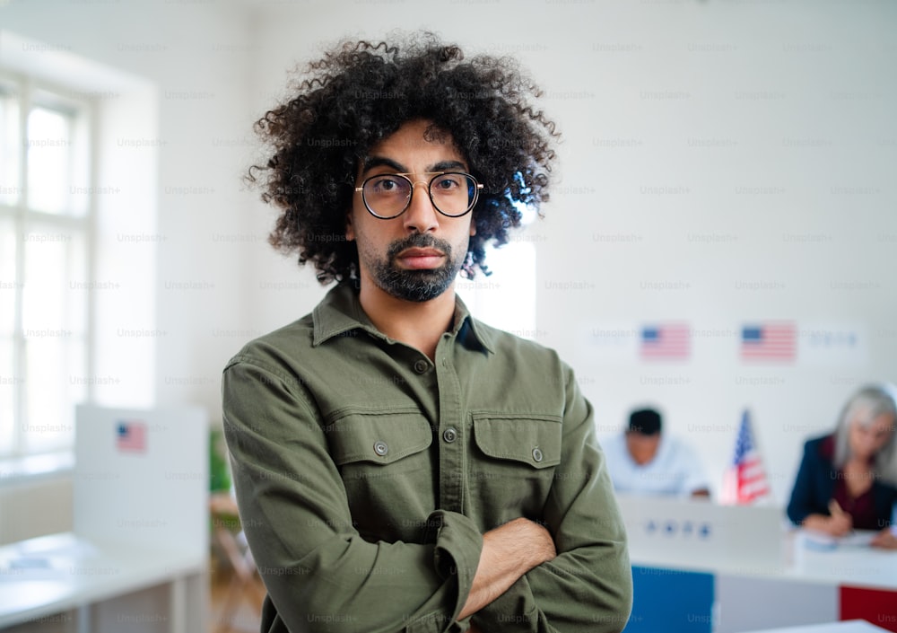 Portrait of serious mixed-race man looking at camera in the polling place, usa elections.