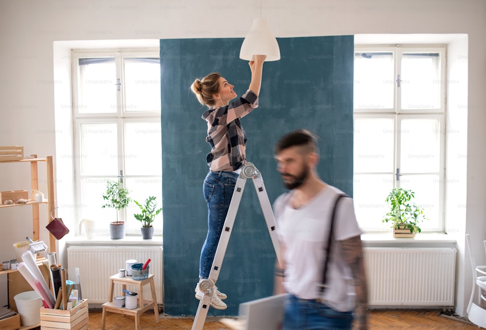 幸せな中期成人のカップルは、自宅で屋内の電球を交換し、移転し、DIYのコンセプトを持っています。
