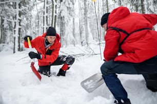 Servicio de rescate de montaña en operación al aire libre en invierno en el bosque, cavando nieve con palas. Concepto de avalancha.