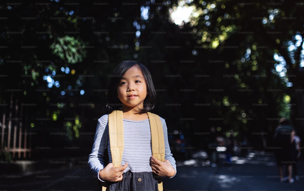 Portrait d’une petite fille japonaise avec un sac à dos marchant à l’extérieur en ville. Espace de copie.