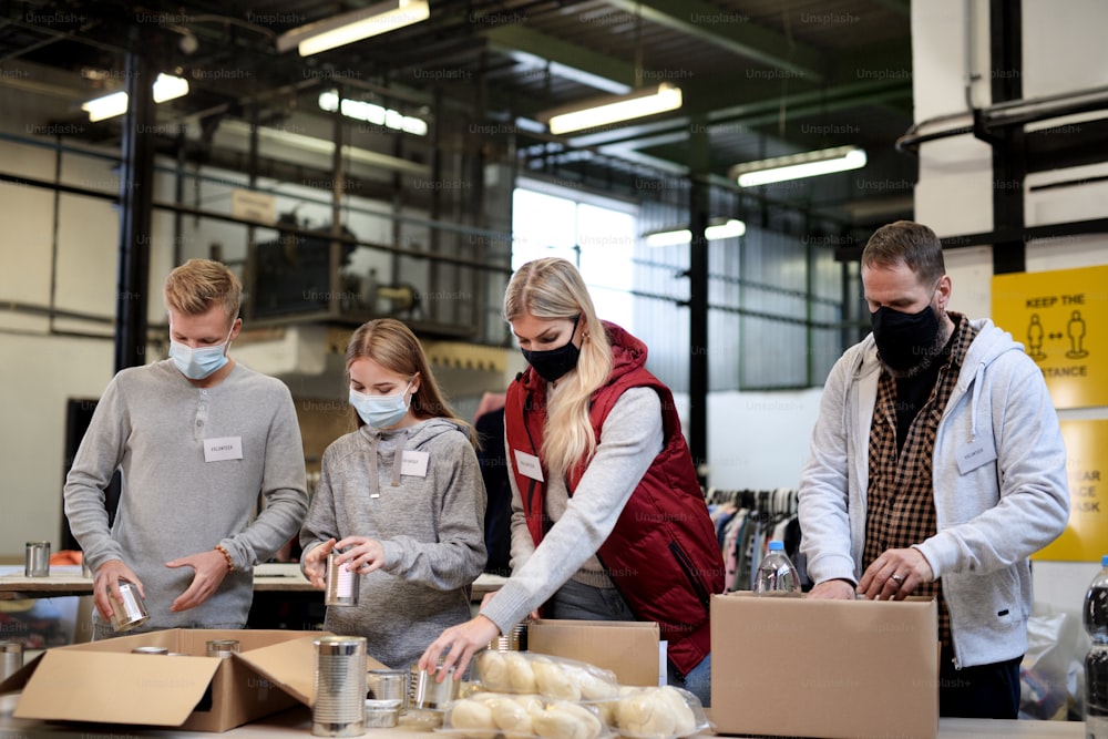 Group of volunteers working in community charity donation center, food bank and coronavirus concept.