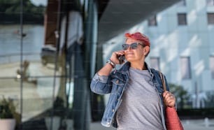 Portrait of senior woman with purple pink hair and smartphone walking outdoors in city or town.