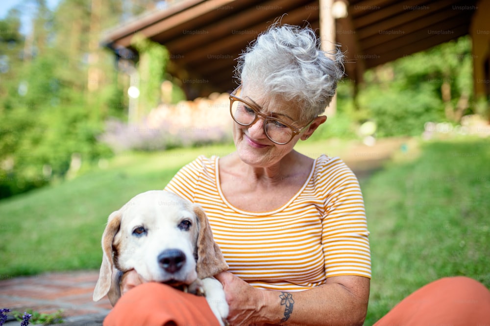 Ritratto di donna anziana seduta all'aperto in giardino, concetto di amicizia del cane da compagnia.