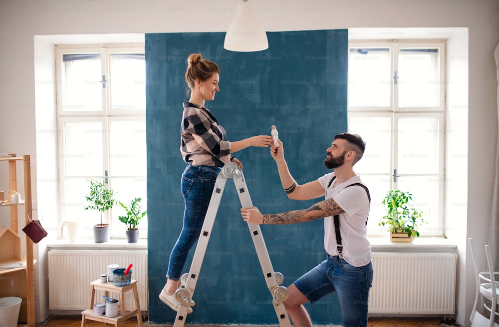 Happy mid adults couple changing light bulb indoors at home, relocation and diy concept.