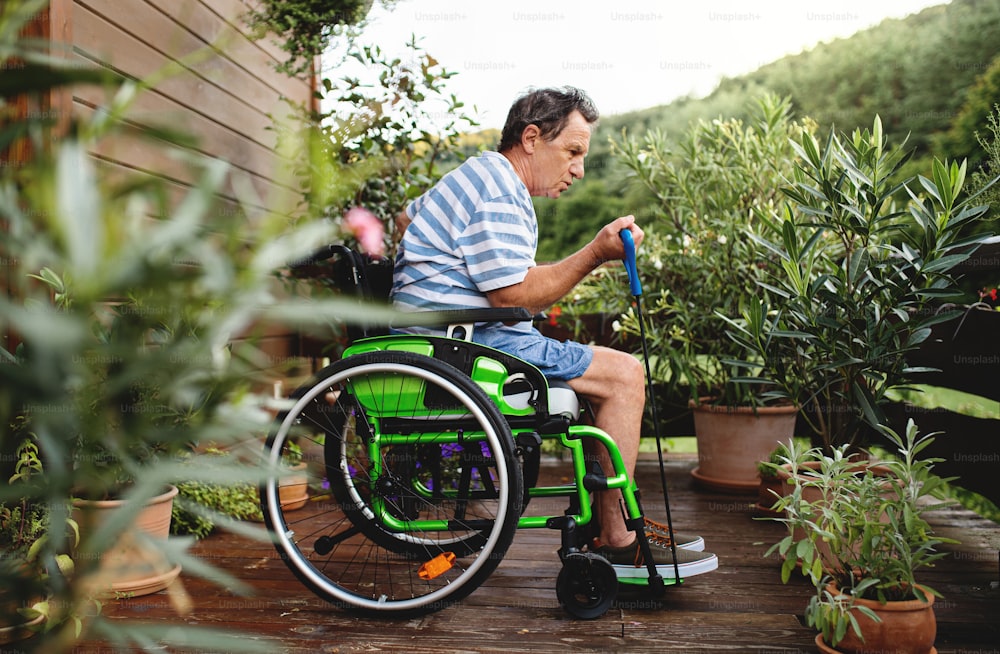 휠체어를 타고 테라스에서 운동을 하는 노인의 측면 모습.