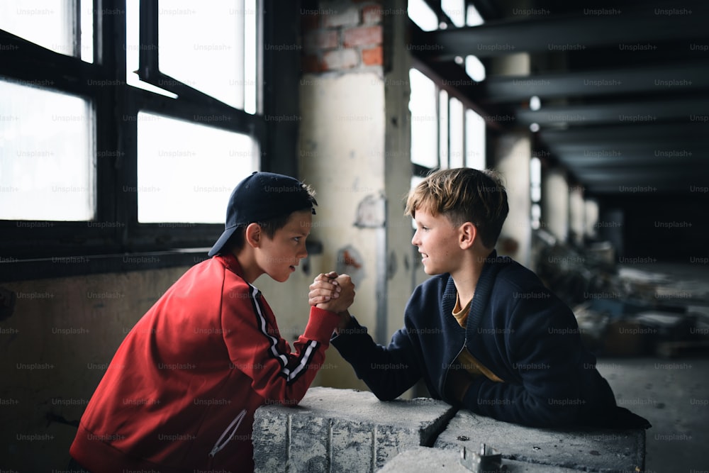 Side view of teenagers boys indoors in abandoned building, arm wrestling.