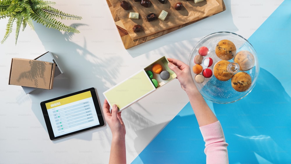 Une vue de dessus d’une femme méconnaissable emballant des biscuits, traitant le concept de bureau des commandes.