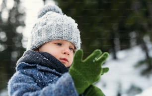 Heureux petit enfant debout dans la neige, vacances dans la nature d’hiver.
