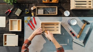 A top view of unrecognizable woman making wooden boxes, small business and desktop concept.