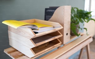 Paper and document wooden tray holders and organisers on desk with plant, natural decor concept.