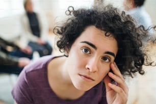 A portrait of young attractive depressed woman during group therapy.