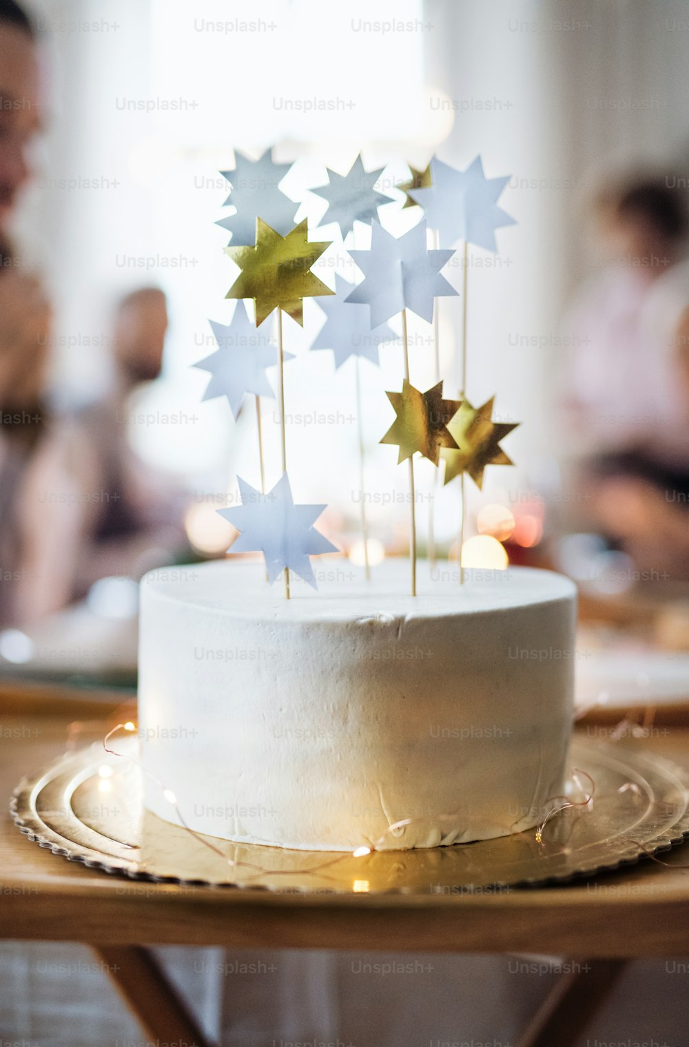 A close-up of white modern birthday cake on a table on an indoor party. Copy space.