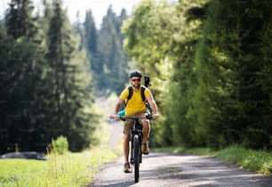 夏の自然の中で屋外でサイクリングする小さな子供を持つ父親の正面図、スロバキアのハイタトラ山脈。
