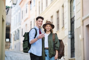 Una pareja joven viaja usando un teléfono inteligente en la ciudad de vacaciones, haciendo turismo.