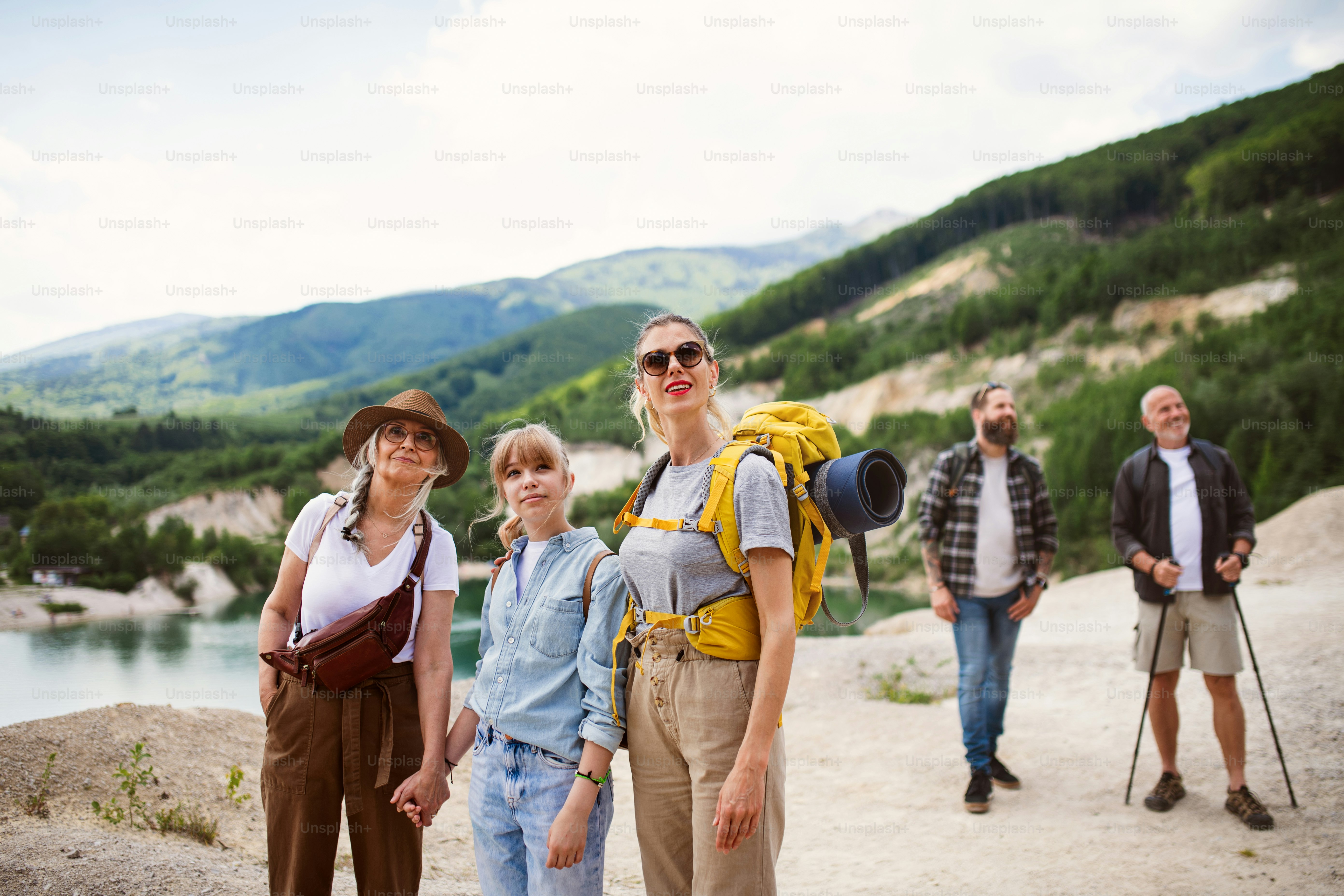 Una familia multigeneracional feliz en un viaje de senderismo en vacaciones de verano, caminando.