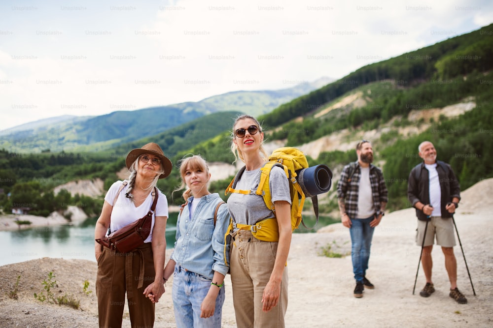 Una felice famiglia multigenerazionale in viaggio escursionistico durante le vacanze estive, a piedi.