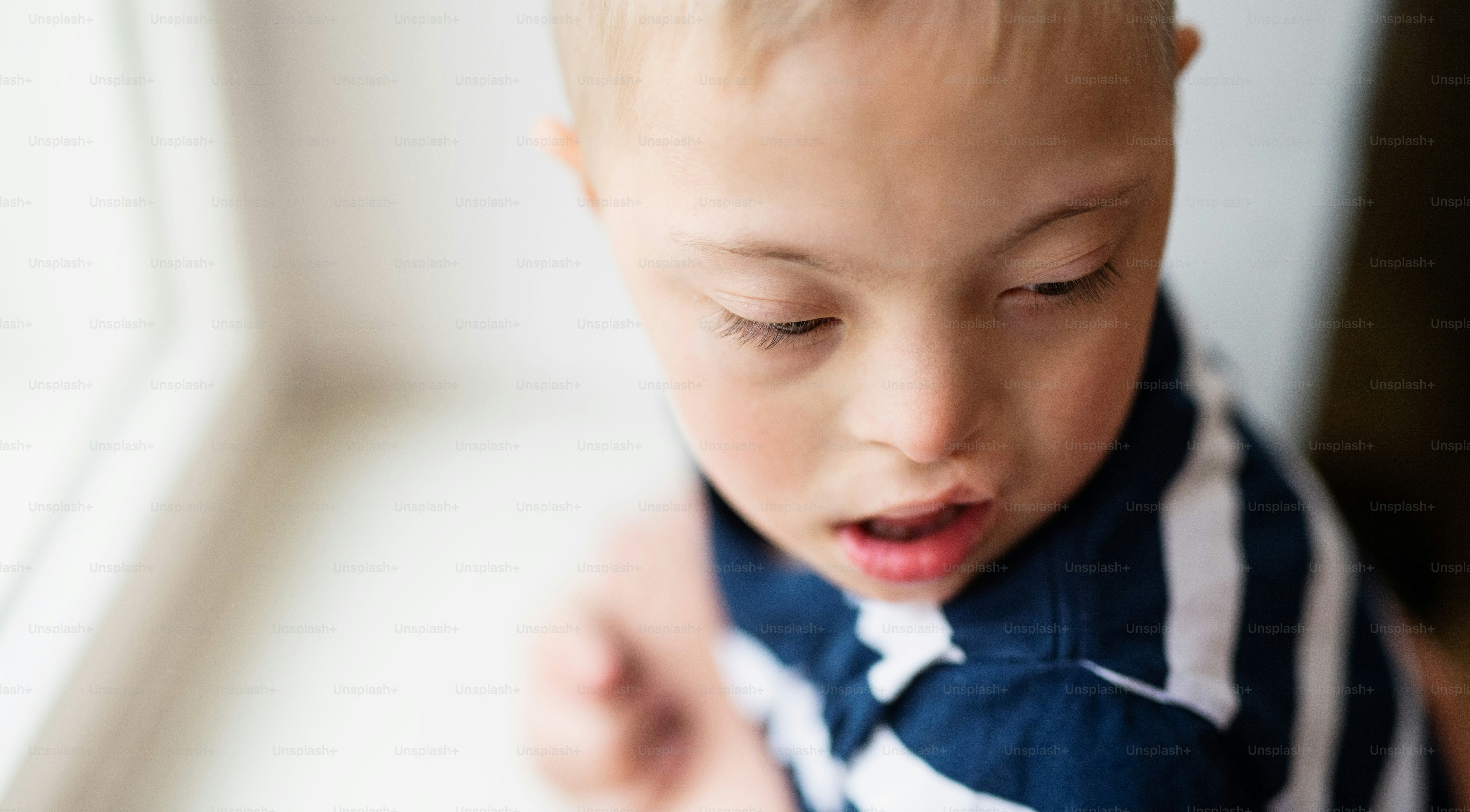 A closeup portrait of down syndrome boy indoors at home. Copy space