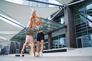 Two happy women doing exercise outdoors in city, healthy lifestyle concept.