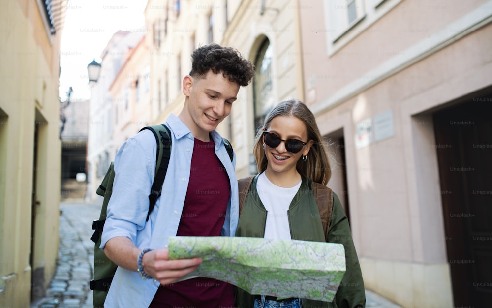 Jovens viajantes casal andando com mapa na cidade em férias, passeios.