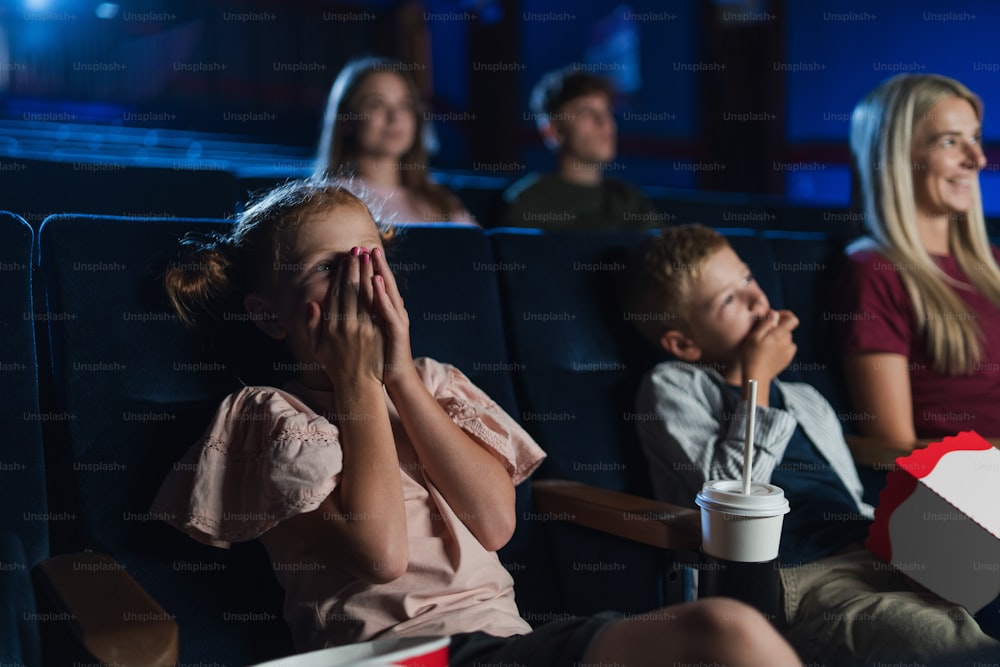 A mother with small children in the cinema, watching film.
