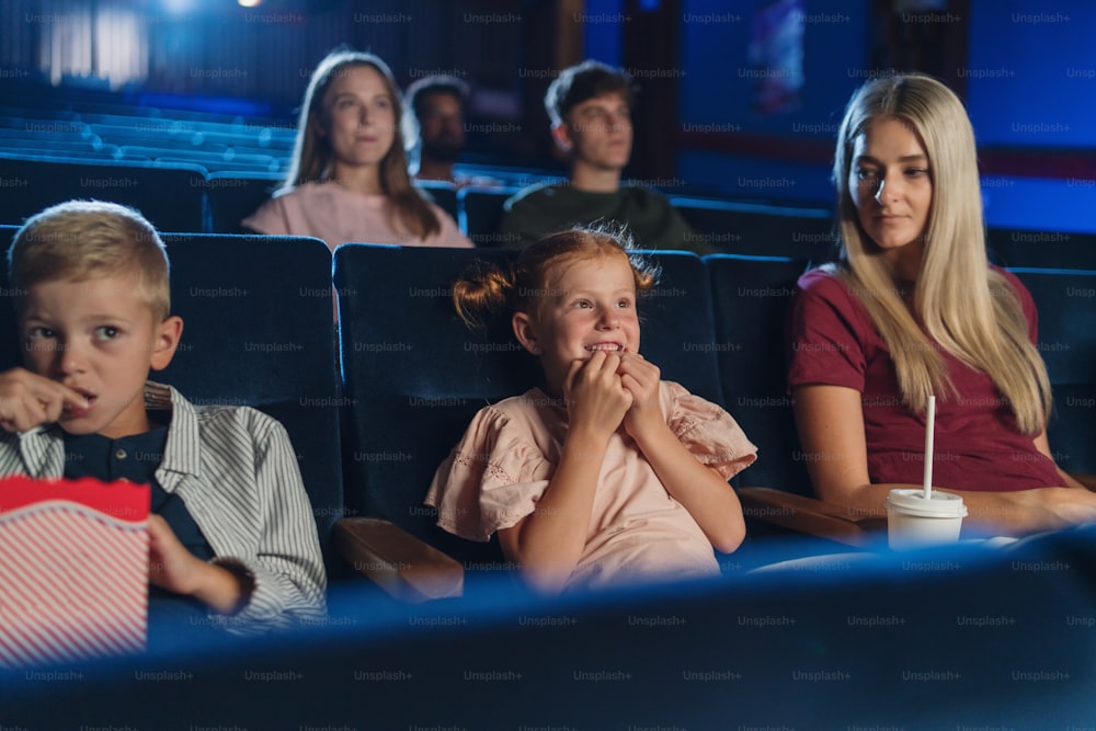 A mother with happy small children in the cinema, watching film.