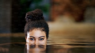 Portrait d’une jeune femme heureuse dans une piscine intérieure, regardant la caméra.