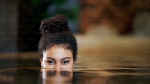 Portrait of happy young woman in indoor swimming pool, looking at camera.