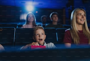 A mother with happy small children in the cinema, watching film.