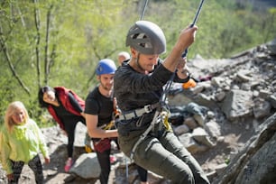 A group of seniors with instructor climbing rocks outdoors in nature, active lifestyle.