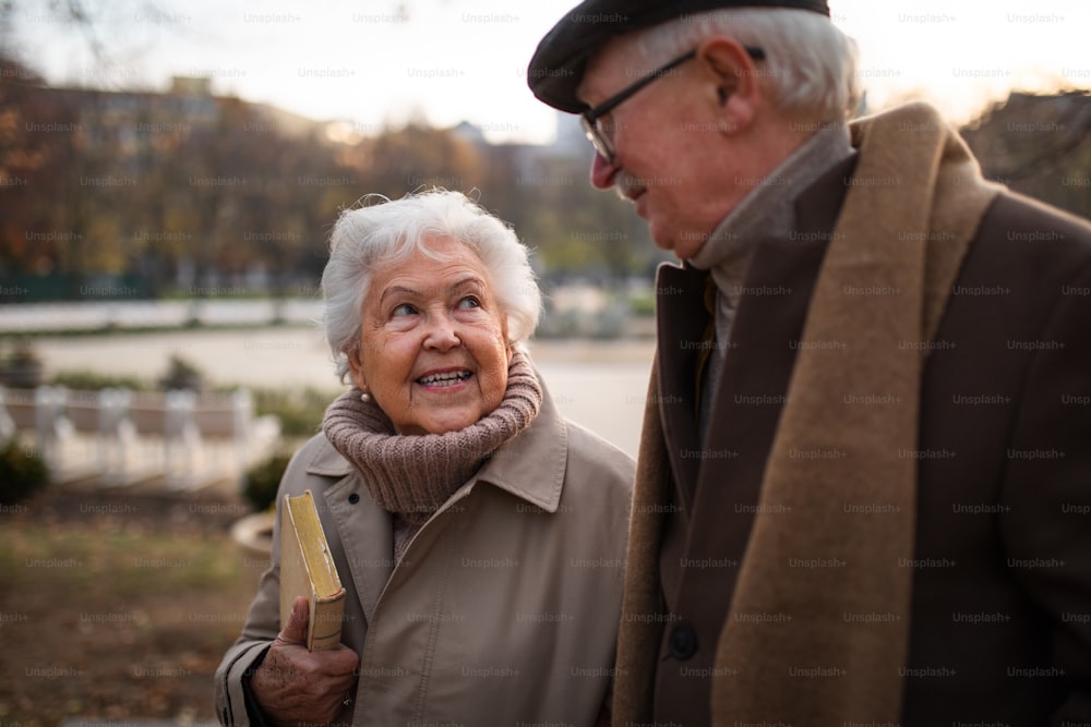 Amici anziani felici durante una passeggiata all'aperto nel parco cittadino in autunno, parlando.
